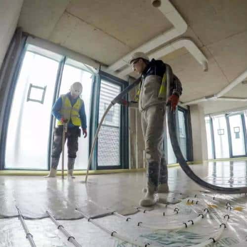Workers installing underfloor heating in new building.