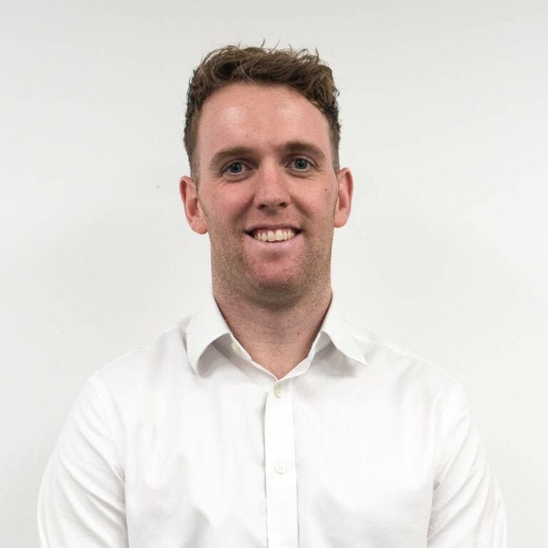 Smiling man in white shirt against white background.