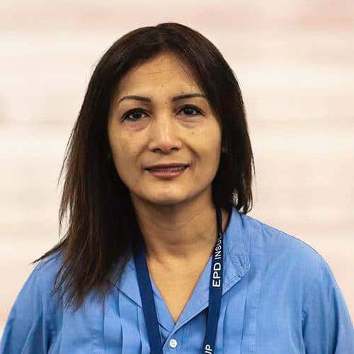 Middle-aged Asian woman in blue shirt and lanyard.