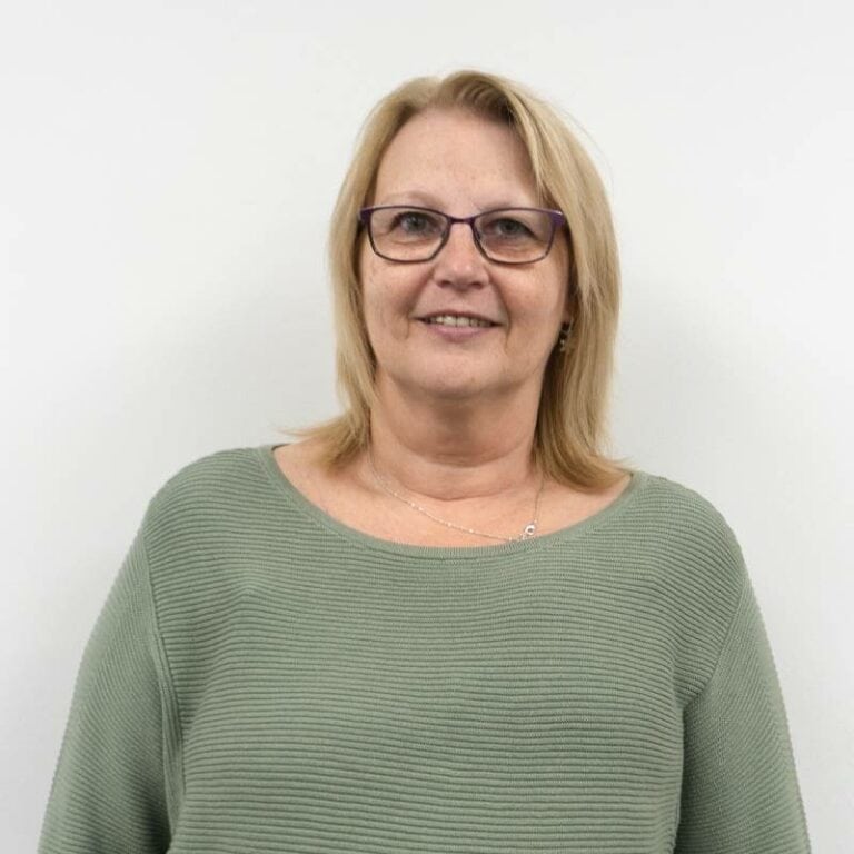 Middle-aged woman smiling in green sweater, white background.