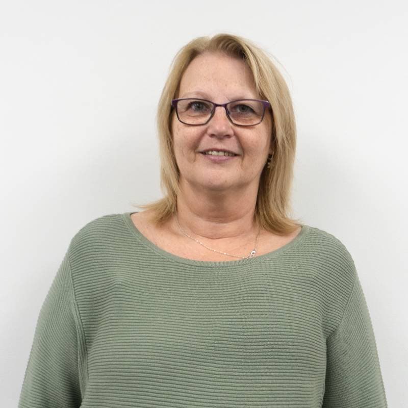 Middle-aged woman smiling in green sweater, white background.