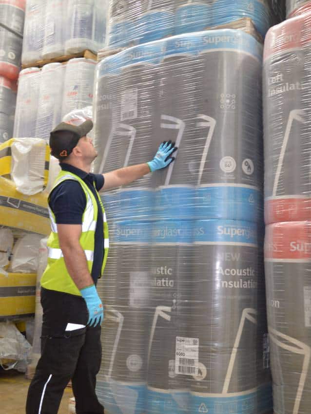 Worker inspecting large rolls of insulation material.