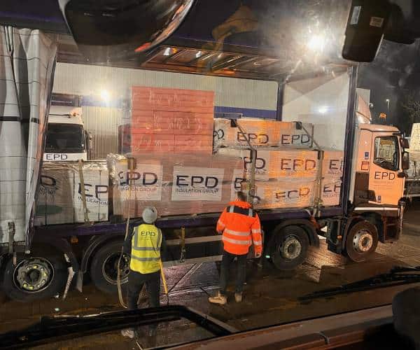Workers loading insulation materials onto lorry at night.