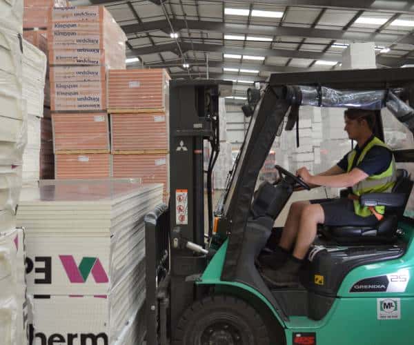 Worker operating forklift in industrial warehouse.