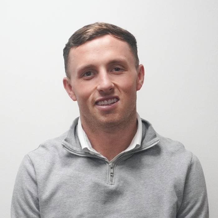 Smiling man in grey zip-up sweater against white background