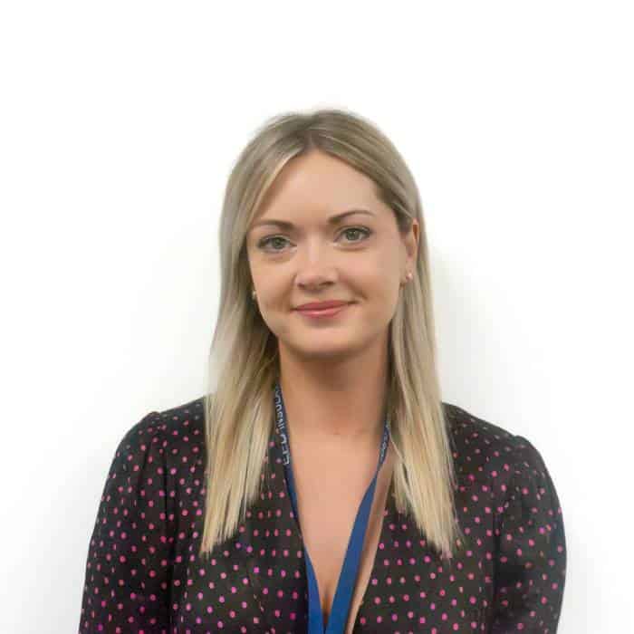 Professional woman smiling in polka dot blouse with lanyard