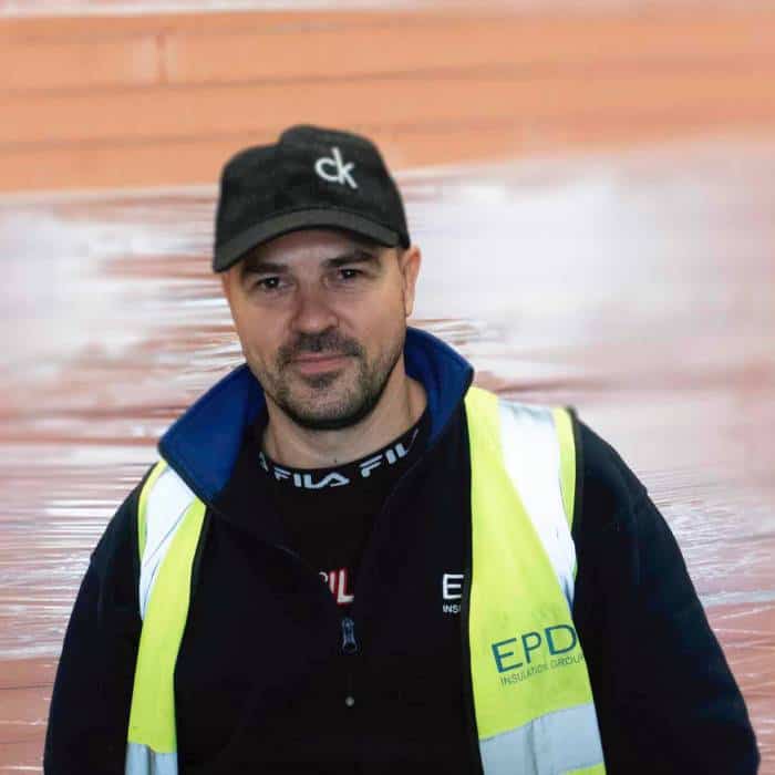 Man with cap and high-vis vest indoors.