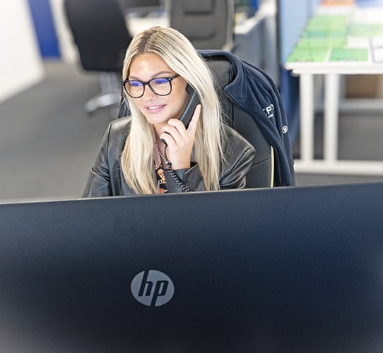 Businesswoman on phone at desk with HP computer