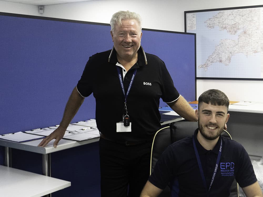 Two office workers smiling in a room with maps